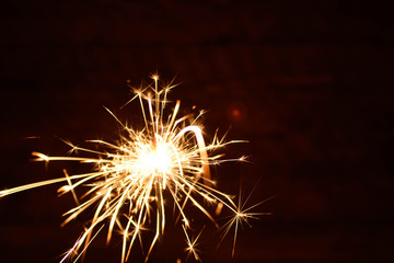 Holiday Bengal lights on the dark background. Burning sparkler, Happy New Year.