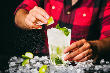 Barman squeezing lime making Mojito cocktail
