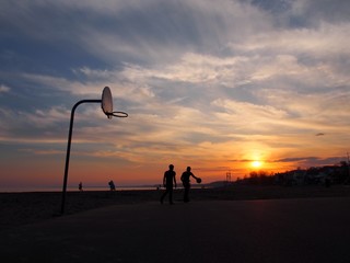 バスケットボールを楽しんでいる人たちと夕日