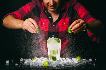 Barman squeezing lime making Mojito cocktail