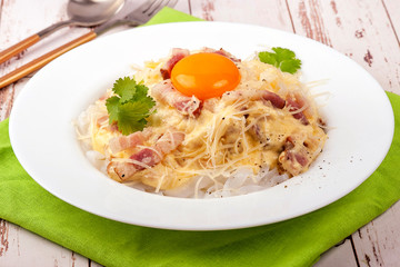Traditional dish of Italian cuisine carbonara sauce with low-carb shirataka paste and egg yolk. Large portion served on a white plate. Close up and horizontal view.