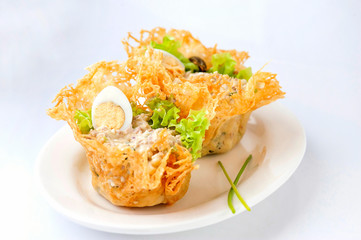 Portioned snack in baked crispy cheese tartlet. Close up and horizontal view.