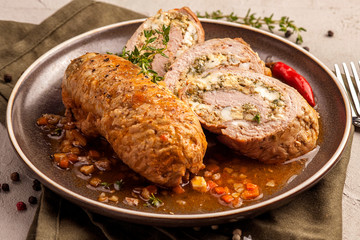 Baked meat rolls in a thick vegetable sauce. A large portion of sliced meat on a plate. Close up and horizontal view.