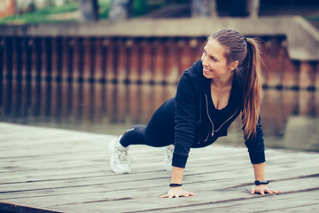 Young beautiful woman doing push up outdoors