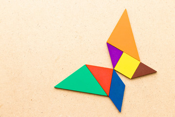 Color tangram in butterfly shape on wood background