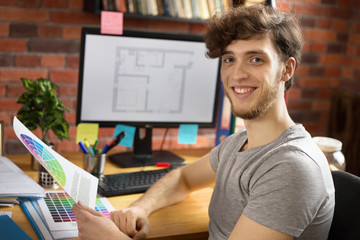 Fototapeta premium Young smiling man working at his workplace