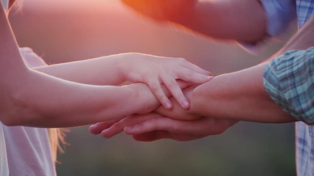 A group of people of different ages puts their hands on one another. Teamwork concept