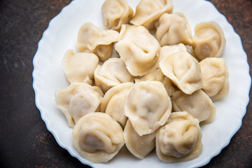 Meat dumplings - russian pelmeni, ravioli with meat on plate on a wooden background