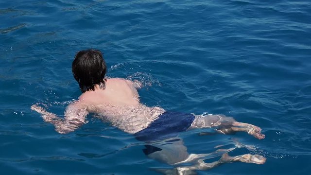 Man in swimsuit is swimming in crystal clear water. Tourist is bathing in sea. Turkey.