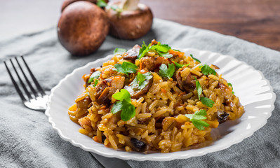 meat with Rice, mushroom and vegetables in white plate on wooden table background