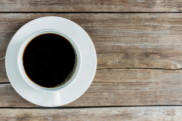 Black coffee, a needle in a white coffee cup, placed on an old wooden table, top view