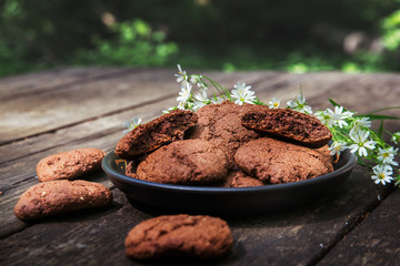 vegetarian chocolate cookies stellaria decorated with flowers are on a wooden table in the environmentally friendly forest