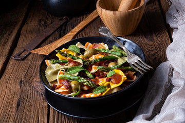 Pasta salad with green asparagus, olives and parma ham