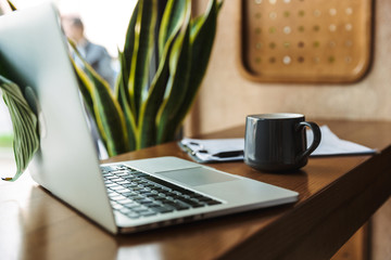 Photo of laptop computer with cup and clipboard on table near window