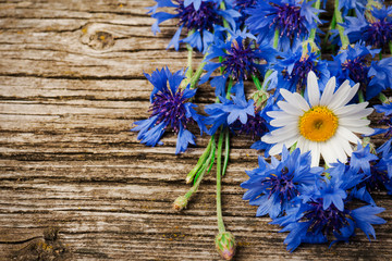 bouquet of blue cornflowers and daisies close-up on a wooden background