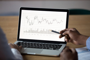 Close up African American businessman analyzing graphs on laptop screen