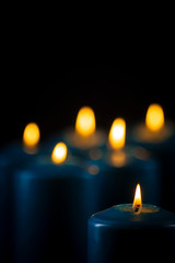 Obraz na płótnie Canvas Lit blue candles on a black background