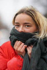 Woman in the city covers her face with the scarf from wind or smog