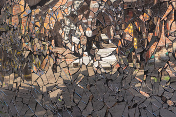 Cracked cement wall with dirty mosaic made from broken mirror pieces with distorted reflection in...