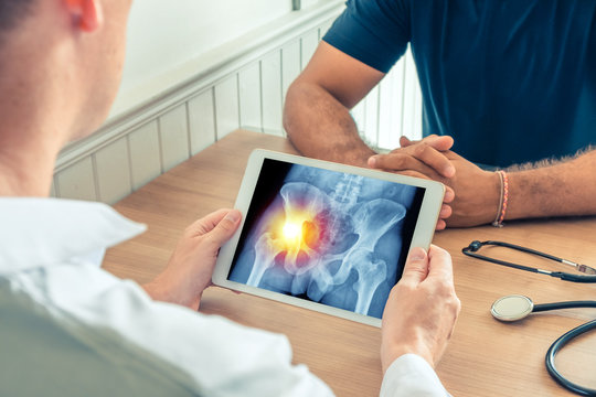 Doctor holding a digital tablet with x-ray of hips of the patient. Pain on the left hip