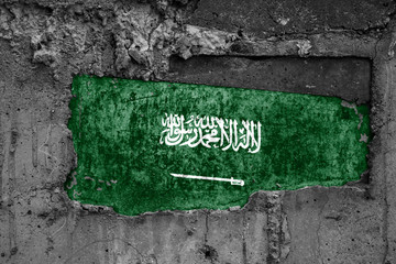 The flag of Saudi Arabia on a dirty wooden surface, built into a concrete base, with scuffs and...