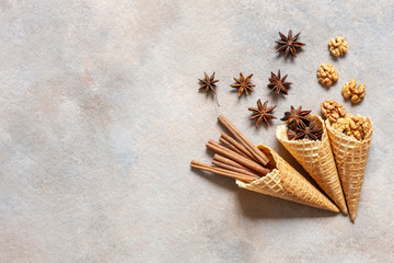 Walnuts, anise and cinnamon sticks in wafer cones. Close-up, top view, flat lay on concrete gray background.