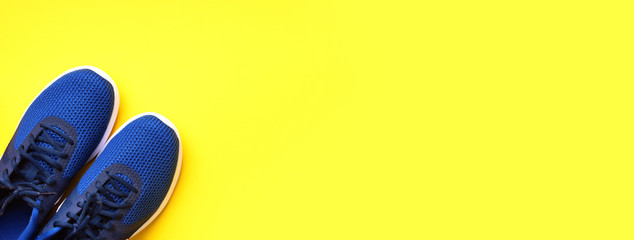 Pair of blue sport shoes on yellow background. Top view, copy space. Fitness, running and sport concept. Healthy lifestyle