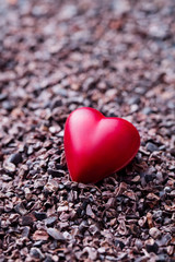 Fototapeta premium Heart shaped chocolate candy on crushed cocoa nibs. Copy space.