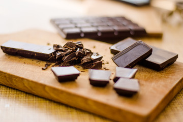 Cut chocolate pieces on the wooden background