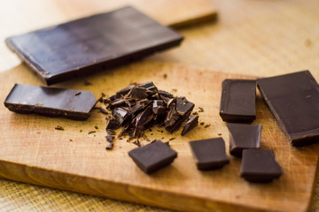Cut chocolate pieces on the wooden background