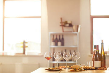 Background image of wine bottles and glasses on table set for tasting session in vineyard lit by sunlight, copy space