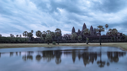A Mystical shot of reflection of Angkor Wat in lake at dawn with a cloudy sky, giving a dynamic and depression feeling. (Siem Reap, Cambodia)