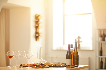 Background image of wine bottles on wooden table in winery lit by sunlight, copy space