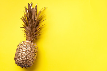 Creative layout. Gold pineapple on yellow background with copy space. Top view. Tropical flat lay. Exotic food concept, crazy trend. Banner