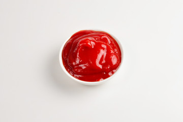 Ketchup in white plate on white background.