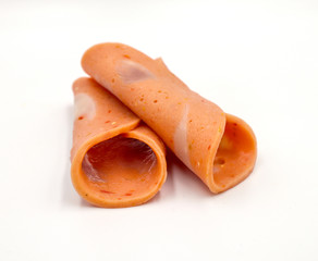 Bologna mixed with fresh chilli and pork ham, slides into a circular plate on a white background