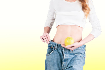 Young woman in jeans weight loss slimming with apple