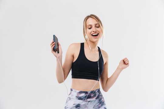 Image of young blond woman 20s dressed in sportswear working out and listening to music with smartphone