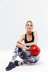 Fototapeta na wymiar Image of delighted blond woman 20s dressed in sportswear working out and doing exercises with fitness ball