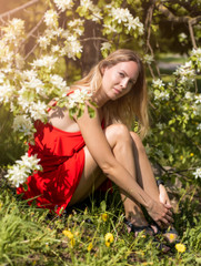 Portrait of a beautiful girl among spring foliage and flowers