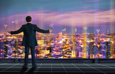Fototapeta na wymiar Vision concept. Successful businessman standing chest, On top of building and looking through Cityscape Skyline Night Light. - Image