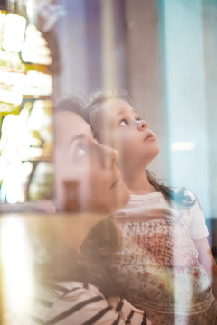 Mother and daughter in a church prying in a catechism education session. Christianity and catholicism concept and empty copy space for Editor's text.