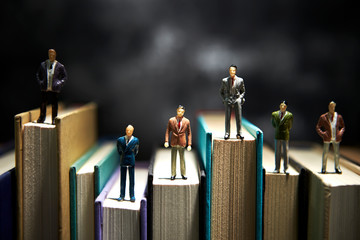 Miniature men on books background 