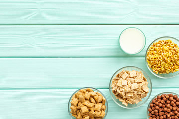 cereals, oatflakes and cornflakes with milk for healthy breakfast on mint wooden background top view mock up