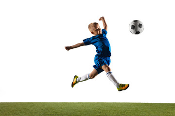 Young boy as a soccer or football player in sportwear making a feint or a kick with the ball for a goal on white studio background. Fit playing boy in action, movement, motion at game.