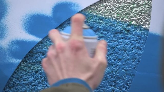 Graffiti artist in the street making art using spray paint and stencil. Stencil street art, urban culture