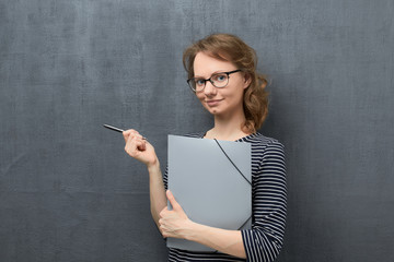 Portrait of young woman holding folder and pen