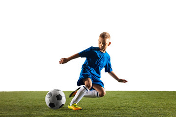 Obraz premium Young boy as a soccer or football player in sportwear making a feint or a kick with the ball for a goal on white studio background. Fit playing boy in action, movement, motion at game.