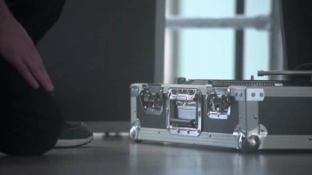 Man opens up aluminum dj travel set case. Portable audio mixing studio equipment in the metallic box