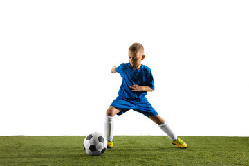 Young boy as a soccer or football player in sportwear making a feint or a kick with the ball for a goal on white studio background. Fit playing boy in action, movement, motion at game. © master1305